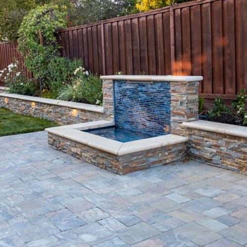 Custom glass tile with stacked natural stone and precast caps