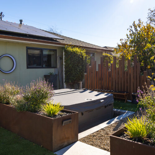 Sunken spa with a privacy screen behind and a corten steel planter in front