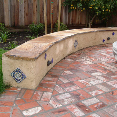 Brick patio with stucco seat wall capped in flagstone